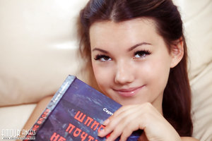 Brunette teen Rogned strips naked in close up while reading a book on a couch